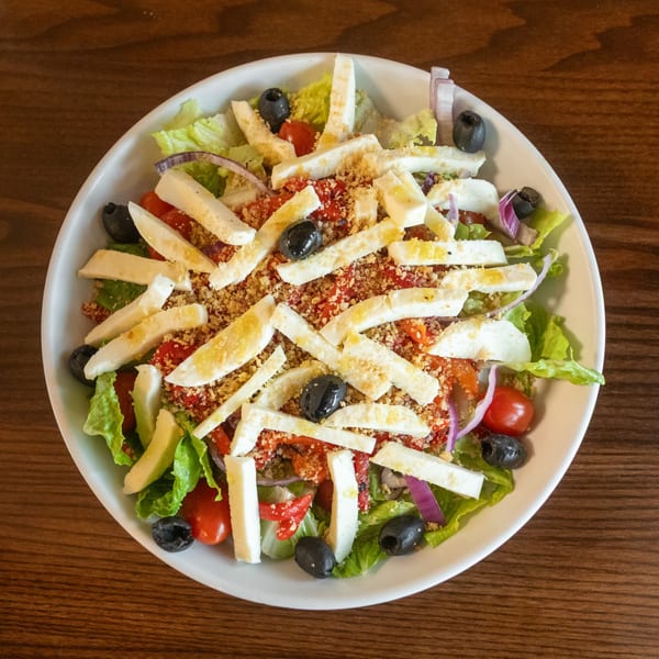 A vibrant State Street Cafe salad with lettuce, tomatoes, olives, red onion, and cheese sticks.