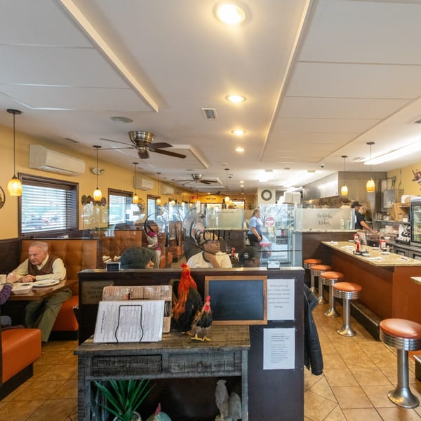 Interior of State Street Cafe with customers dining, a counter with stools, and an open kitchen.