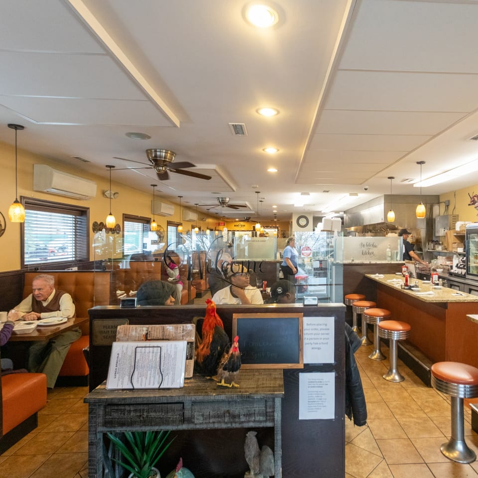 Interior of State Street Cafe with customers dining, a counter with stools, and an open kitchen.
