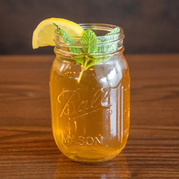 Iced tea in a mason jar, garnished with a lemon slice and fresh mint sprigs.